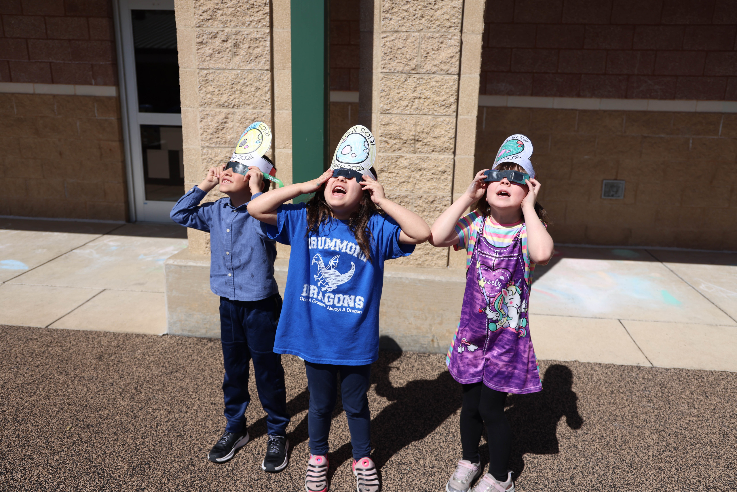 Students stand outside and watch the solar eclipse.