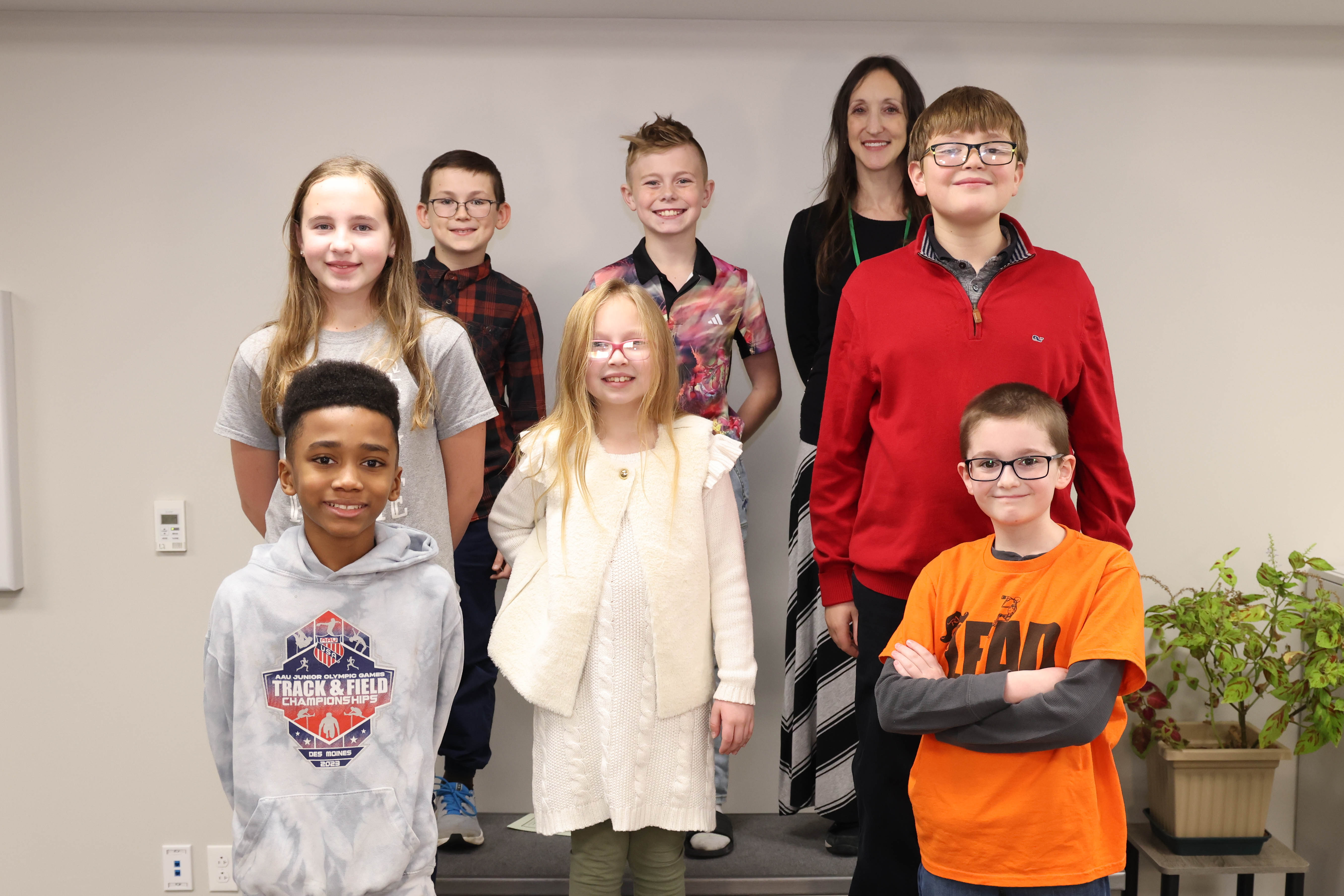 A group of students and one teacher are shown standing next to each other at a recognition program.